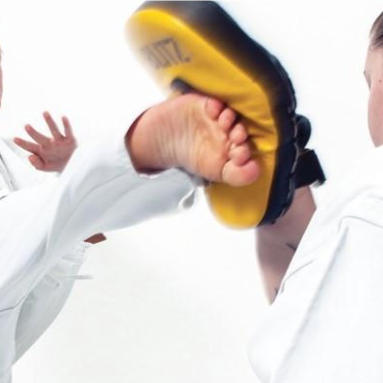 Karate student kicking a pad