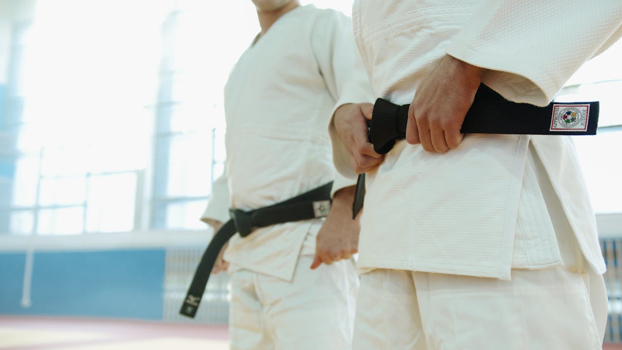 Close-Up Shot of Two People Wearing Karate gi and Black Belt